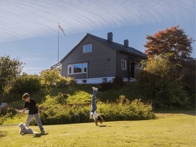 To barn som leker seg i hagen bak huset.